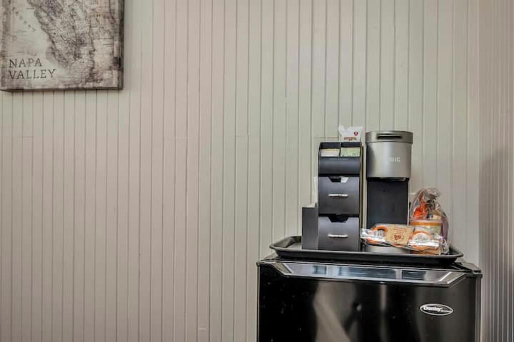 A self-service beverage station with a coffee maker and a tea dispenser, and a tray with snacks.