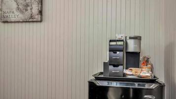 A self-service beverage station with a coffee maker and a tea dispenser, and a tray with snacks.