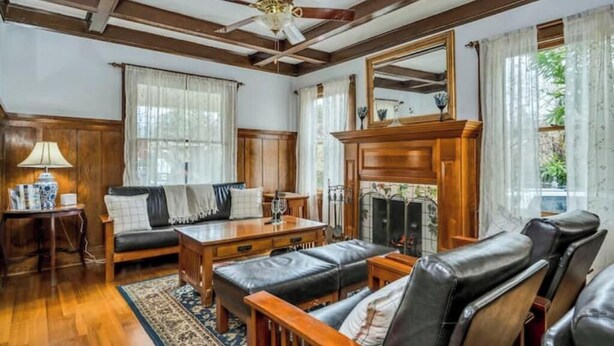 A traditional living room with a fireplace, wooden furniture, and a ceiling fan. - Charming Queen Room near Downtown Calistoga. (Calistoga)