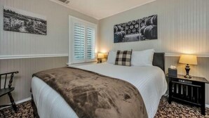 A hotel room with a large bed, two bedside tables with lamps, a chair, and artwork on the walls. - Charming Queen Room near Downtown Calistoga. (Calistoga)