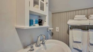 A bathroom with a white sink, a mirror, and a towel rack with folded towels. - Charming Queen Room near Downtown Calistoga. (Calistoga)