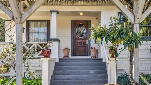 A porch with steps leading to a door, surrounded by potted plants and a wooden railing. - Luxury King Room. Steps to Napa Valley Wineries, Spas & Fine Dining! (Calistoga)