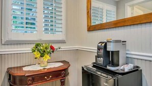 A bathroom with a wooden vanity, a coffee maker, and a mirror. - Luxury King Room. Steps to Napa Valley Wineries, Spas & Fine Dining! (Calistoga)