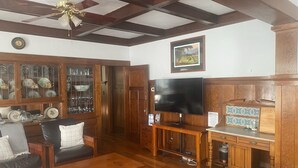 Un salon meublé de meubles en bois, avec un téléviseur et un meuble dont les portes sont en verre.