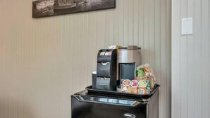 Un espace de libre-service proposant des boissons, avec une machine à café, un distributeur d’eau chaude et un présentoir réfrigéré contenant des en-cas.