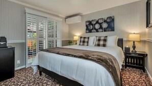 Ein Hotelzimmer mit einem großen Bett, einem Schreibtisch, einem Sessel und einem Fenster mit Jalousien.
