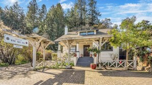 A rustic building with a covered porch, a sign for Wine Way Inn, and a paved driveway. - Charming King Room, Private Entrance and Garden Area. Pet-Friendly! (Calistoga)