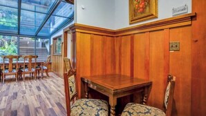 Una habitación con un muro revestido de madera, una mesa de madera con dos sillas y un techo de vidrio.