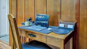 A wooden desk with a laptop, a mug, and a pencil holder.