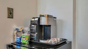 A coffee machine with a tray of snacks and a small refrigerator.
