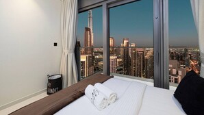 Une chambre d’hôtel avec un grand lit, une vue sur les toits de la ville et un seau étiqueté « linge sale ».