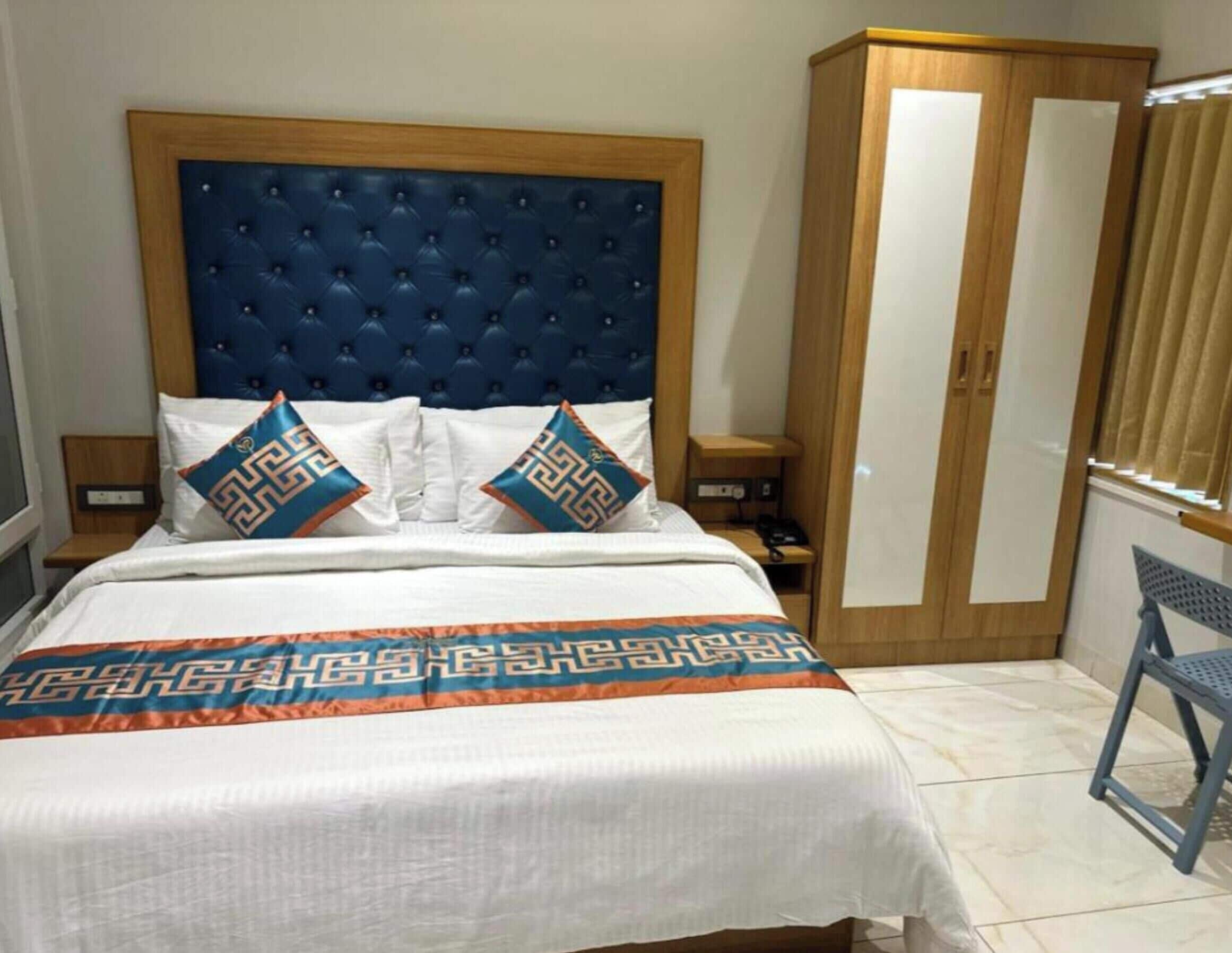 Een slaapkamer met een groot bed, een houten garderobe, een nachtkastje en een stoel.