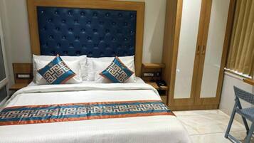 Een slaapkamer met een groot bed, een houten garderobe, een nachtkastje en een stoel.