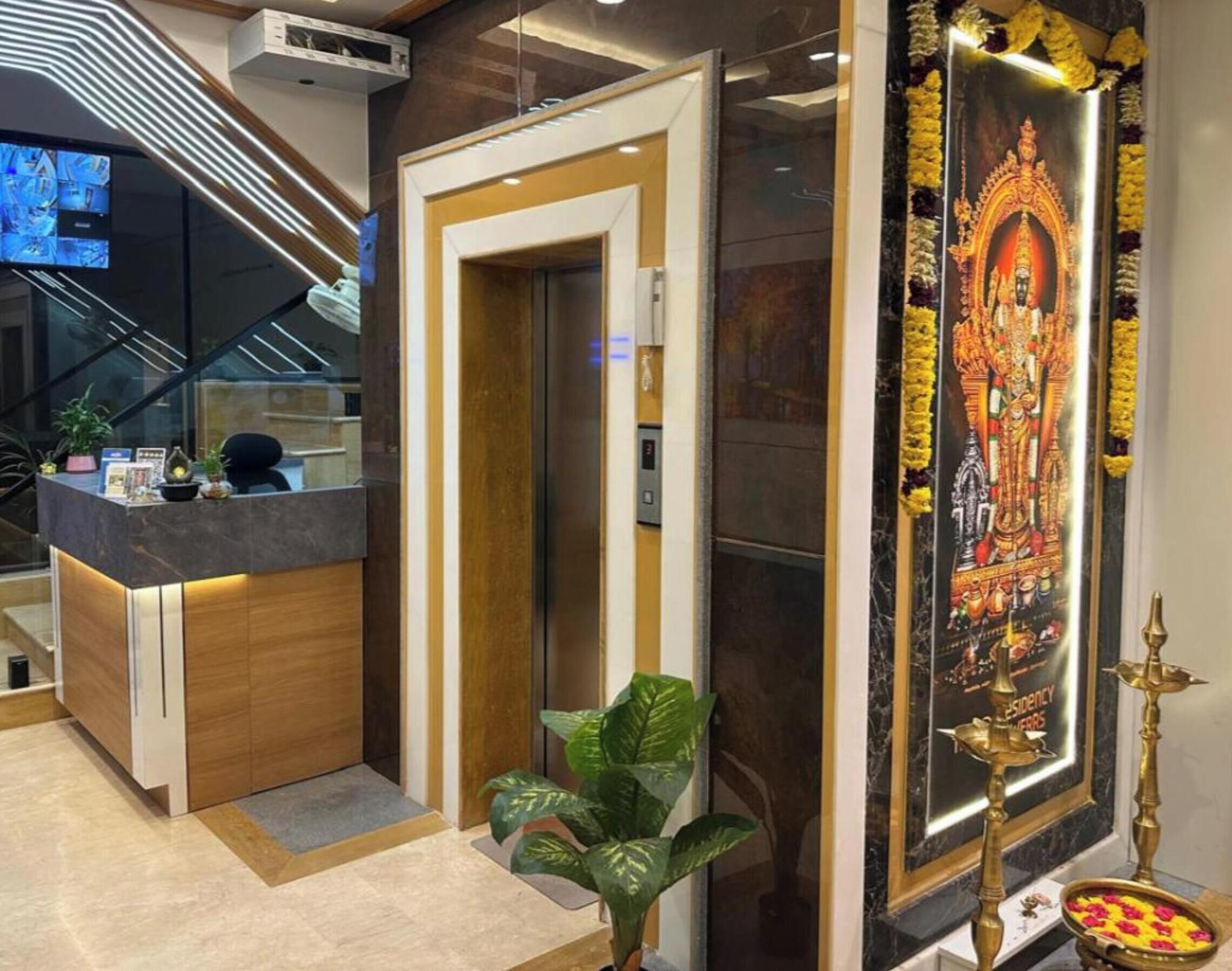 Un espace d’accueil au design moderne, comprenant un comptoir de réception, un escalier et une affiche religieuse encadrée.