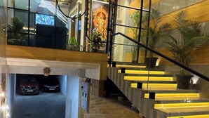 A modern interior with a staircase, a car parked in a garage, and a decorative wall. - THE VP RESIDENCY TOWERRS (Thiruthani)