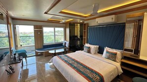 A modern hotel room with a large bed, a seating area by the window, and a desk with a chair. - THE VP RESIDENCY TOWERRS (Thiruthani)