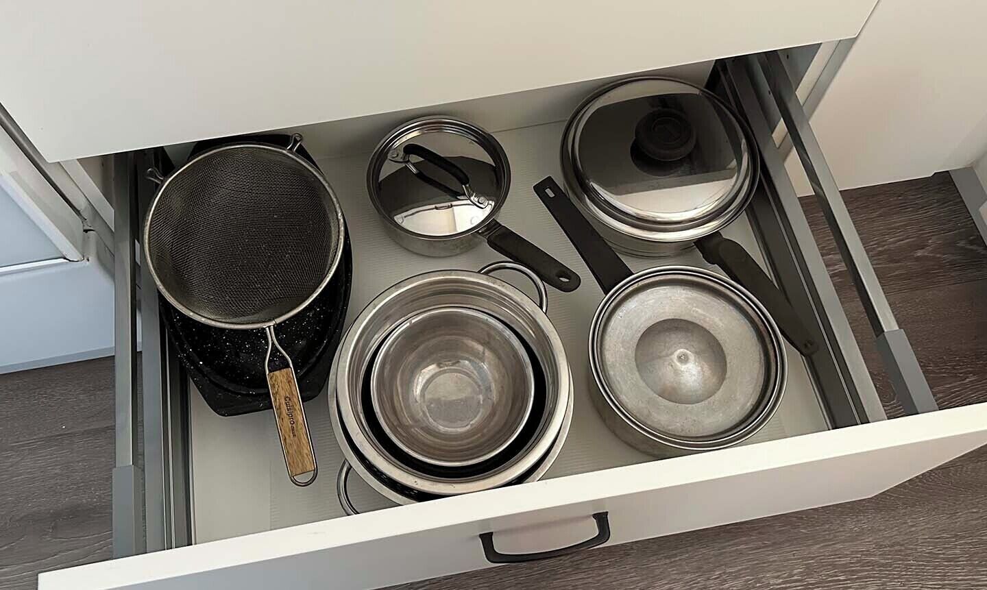 A kitchen drawer with pots and pans.