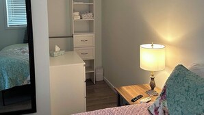 A bedroom with a bed, a bedside table with a lamp, a wardrobe, and a mirror. - Private suite steps away from the ferry and some of Powell River's best dining. (Powell River)