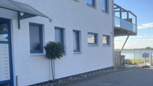 Un bâtiment blanc avec de nombreuses fenêtres et un petit arbre devant.