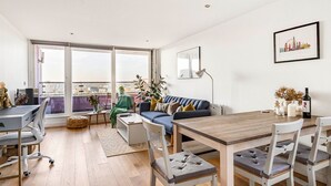 A modern living room with a dining area, large windows, and a city view.