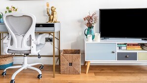 A modern home office with a desk, chair, TV, and bookshelf.