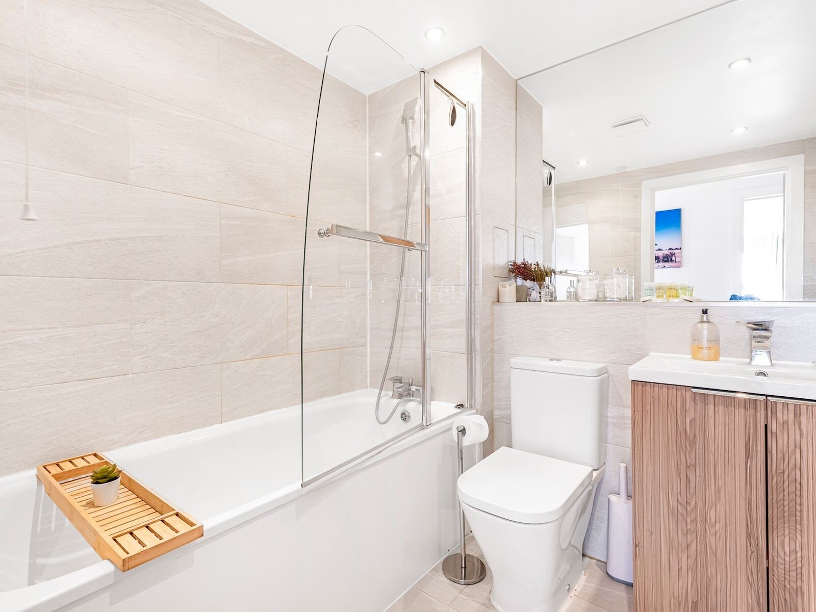 Une salle de bain moderne avec une douche à parois de verre, des toilettes blanches et un meuble-lavabo en bois avec un miroir.