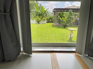 A room with a large window, curtains, and a wooden floor. - Cozy 2 Bedroom Sebring Garden Retreat ~ Private Entrance ~ AC and Wi-Fi (Sebring)