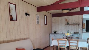 Ein gemütliches Wohnzimmer mit einer Couch, einem kleinen runden Tisch und einem Essbereich mit Stühlen und Tisch.