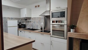 Eine moderne Küche mit weißen Schränken, Backofen, Mikrowelle und Kaffeemaschine.