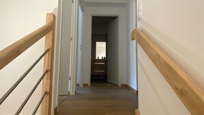 A wooden staircase with a handrail leading to a room with a closet and a window.