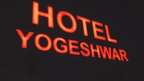 Ein Schild mit dem Schriftzug 'HOTEL YOGESHWAR' in roter Schrift.