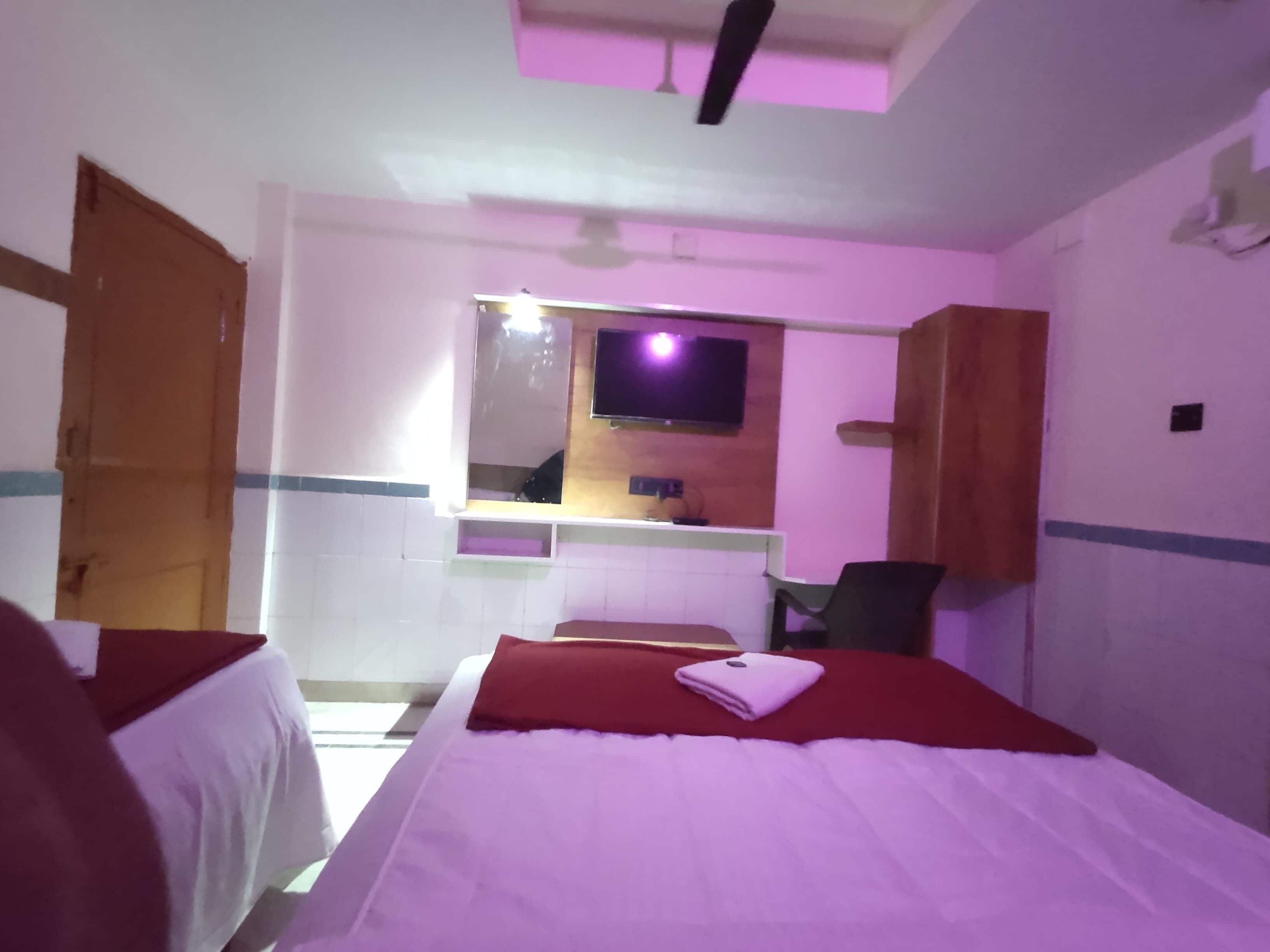 Una habitación de hotel con una cama, una silla, un televisor y un espejo.