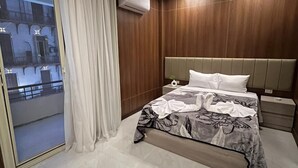 A modern bedroom with a large bed, a nightstand, a built-in air conditioning unit, and a view of a balcony. - Royal Home Hotel (Cairo)