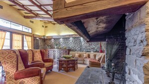 Un salón acogedor con chimenea de piedra, asientos cómodos y techo rústico.