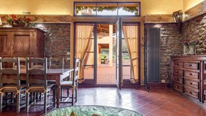 Un espacio amplio con comedor, chimenea de piedra y vistas del patio exterior.