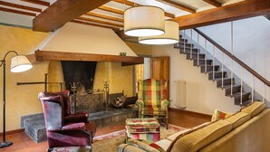 Una sala de estar acogedora con chimenea, una escalera y un ventanal grande.