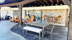An outdoor patio with wooden chairs and tables, a stone wall, and a covered area with a wooden ceiling. - Come enjoy the breathtaking views from the High Country Retreat (Mead)