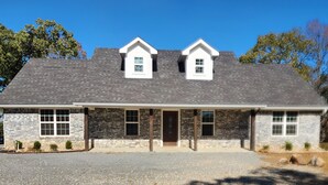 A two-story house with a stone facade, a front porch, and a garage. - Come enjoy the breathtaking views from the High Country Retreat (Mead)