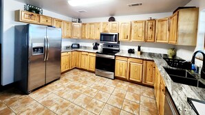 A modern kitchen with wooden cabinets, stainless steel appliances, and a tiled floor. - Come enjoy the breathtaking views from the High Country Retreat (Mead)