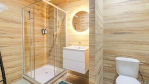 Une salle de bain moderne avec une douche à parois de verre, un lavabo blanc et des toilettes.
