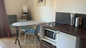 A compact kitchen with a marble-top table, a microwave, and a refrigerator.