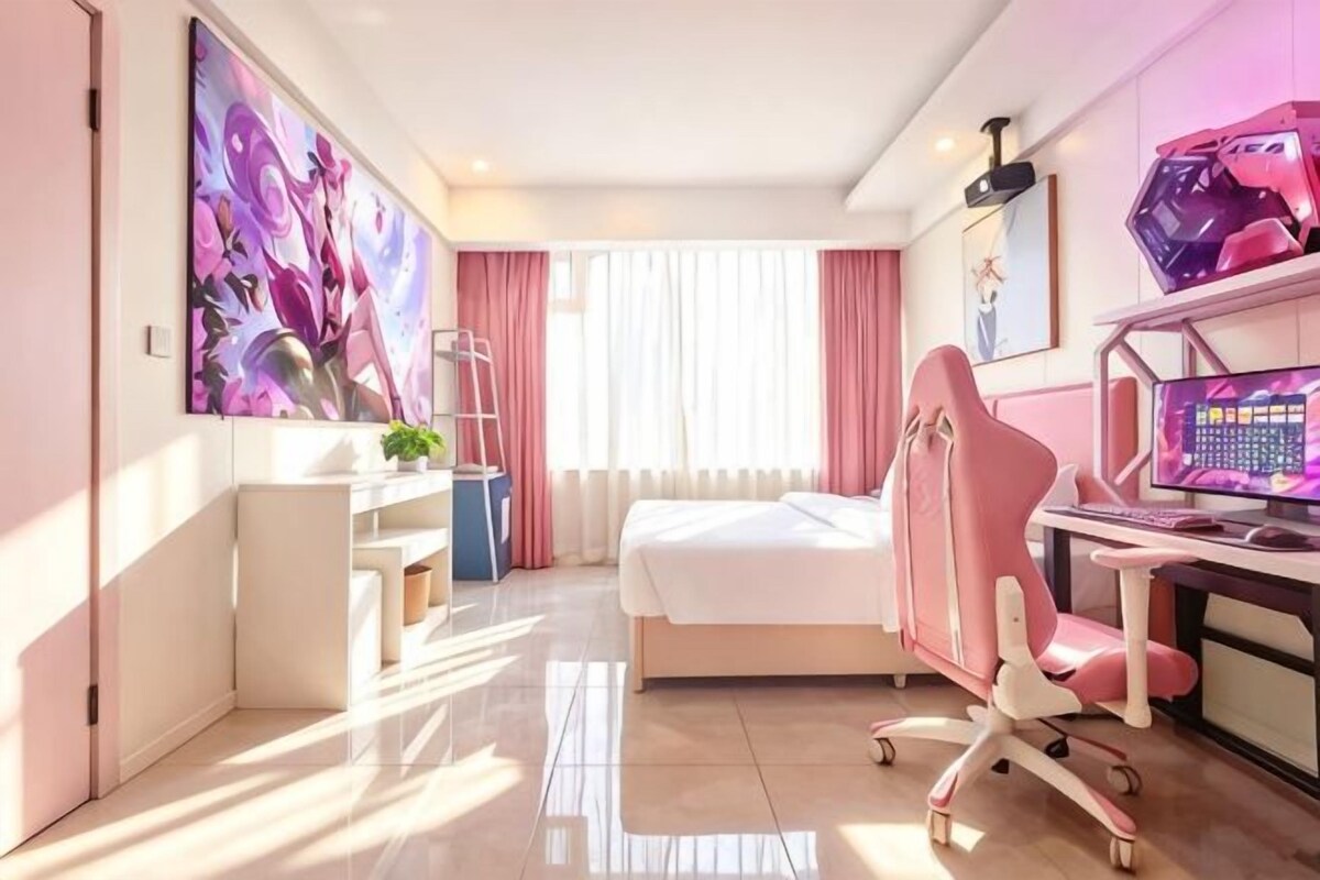 Habitació d'hotel moderna amb llit, escriptori, ordinador i obra d'art.