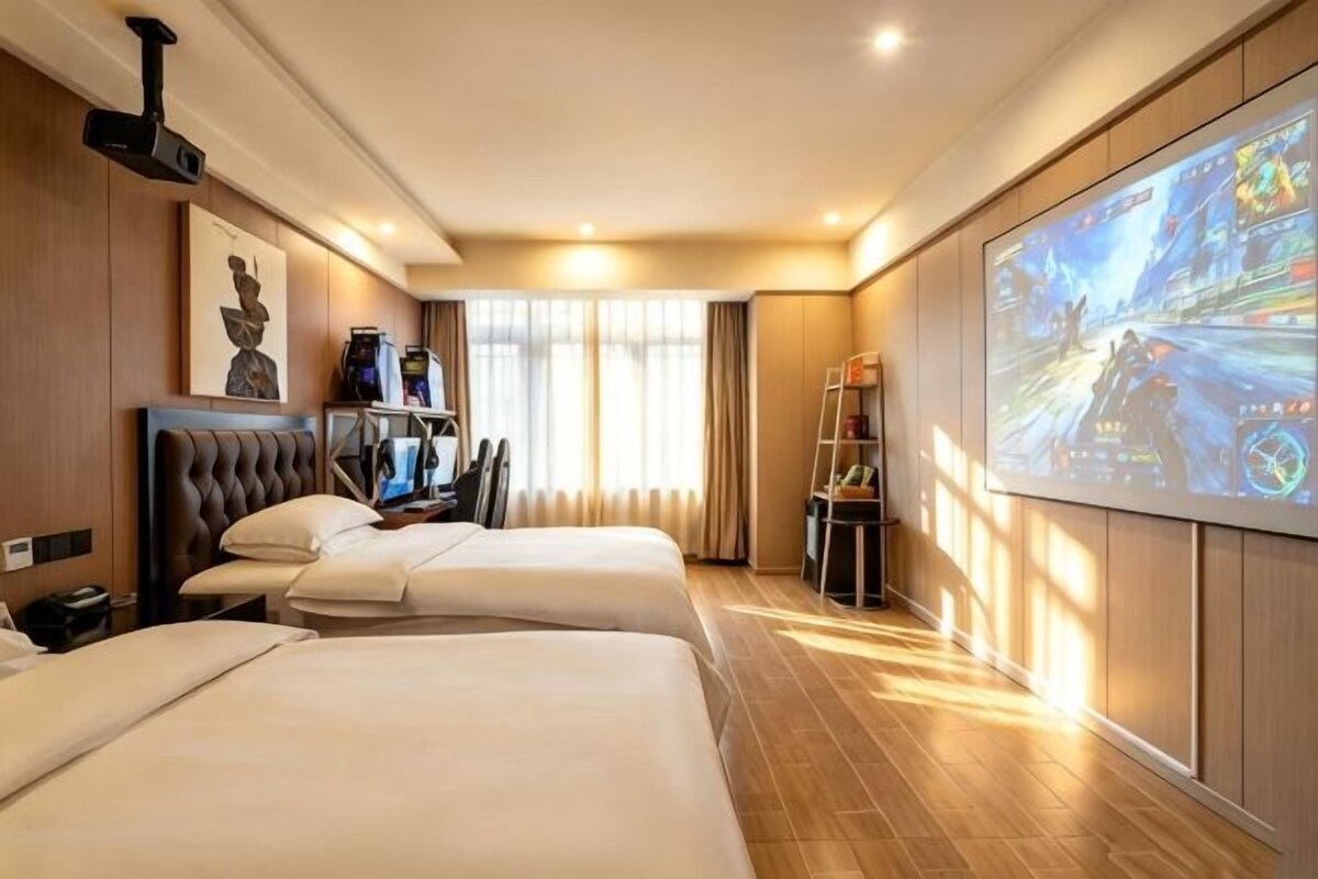 Habitació d'hotel amb dos llits, televisió, escriptori amb cadira i finestra amb cortines.