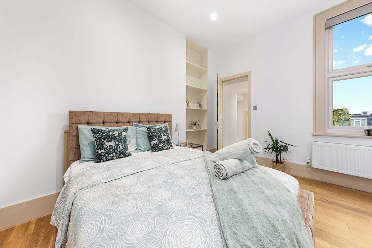 Ein Schlafzimmer mit Bett, Fenster und einer Pflanze.