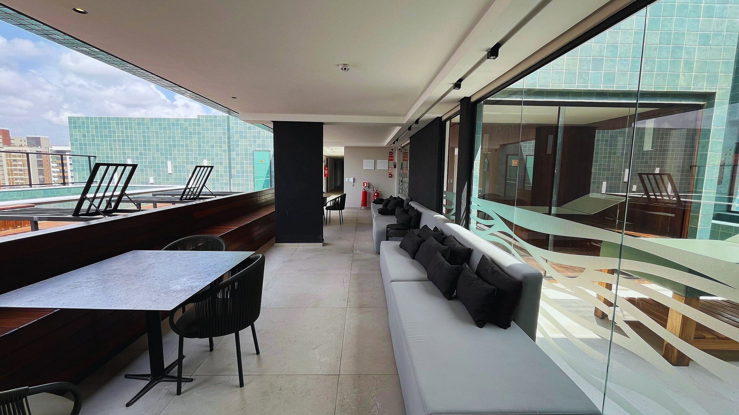 Un balcon moderne avec un long canapé, une table à manger et des chaises.