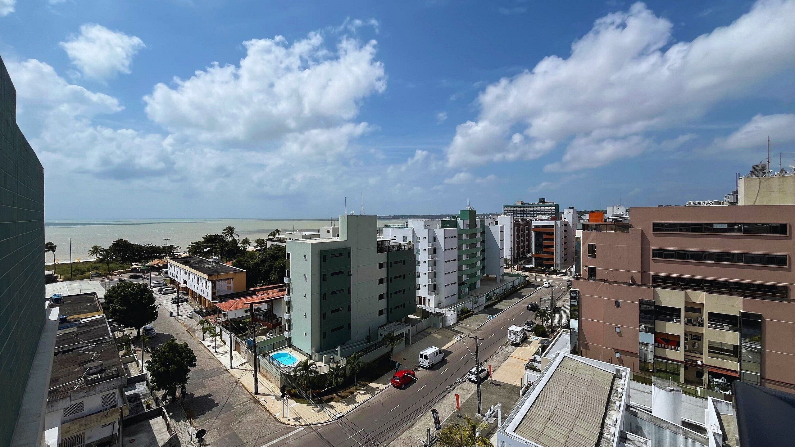 Un paysage urbain avec des bâtiments modernes, un ciel dégagé et une vue sur l’océan.