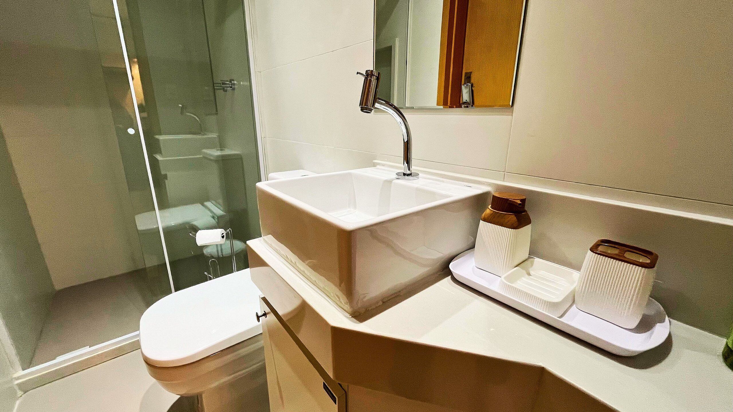 A modern bathroom with a glass shower enclosure, a white sink, and a toilet.