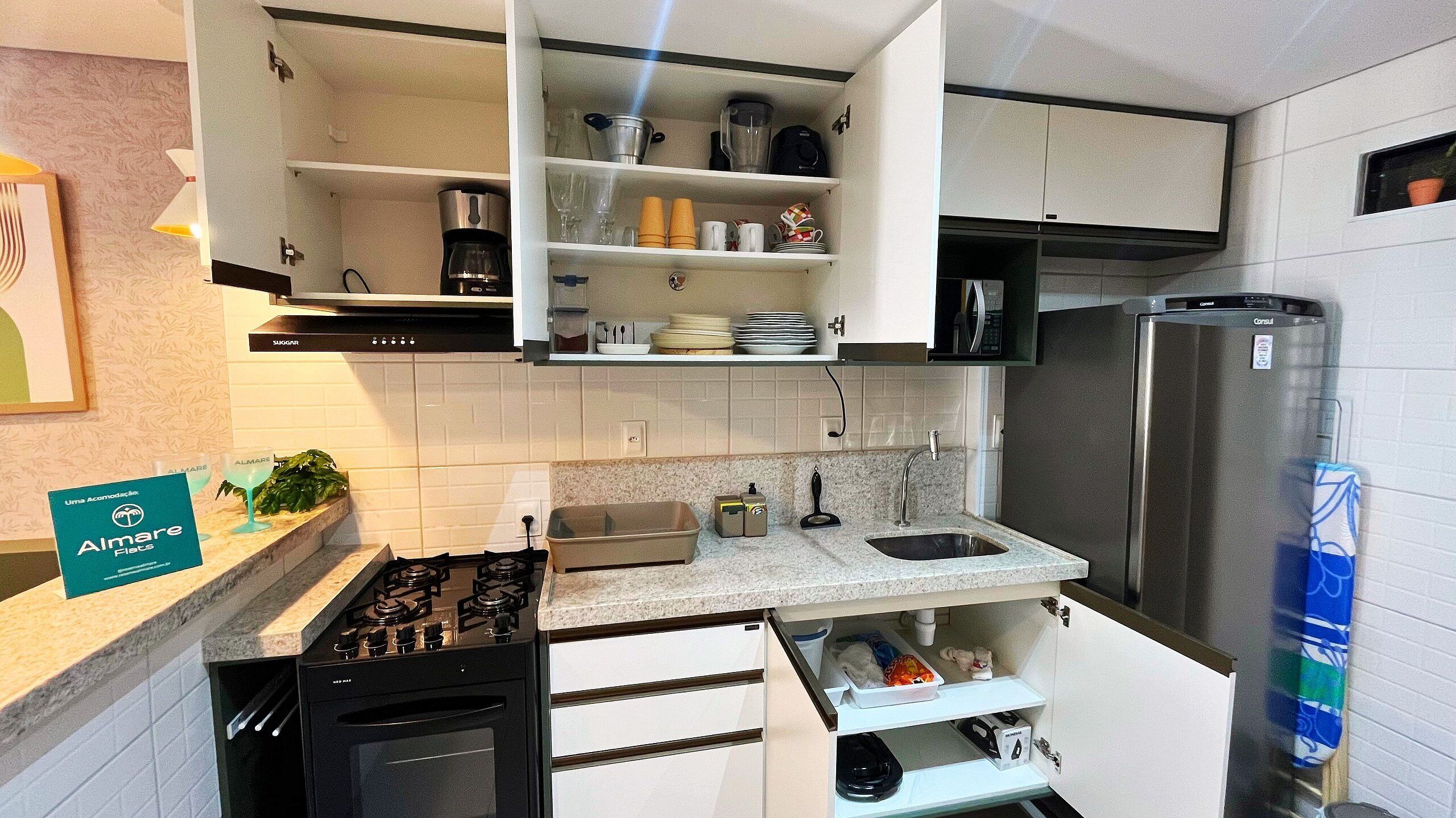 Una cocina moderna con armarios blancos, un refrigerador de acero inoxidable, una estufa a gas y un fregadero.