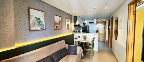 A modern living area with a sofa, dining table, and kitchen in the background.