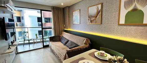 A modern living room with a sofa, dining table, and artwork on the walls.